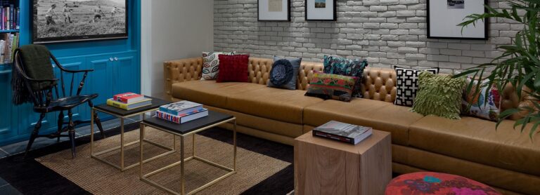 מבט על חלק מהלובי ופינת הקריאה ב- מלון סנטר שיק תל אביב עם הספה המעוצבת ושטיחים ושולחנות