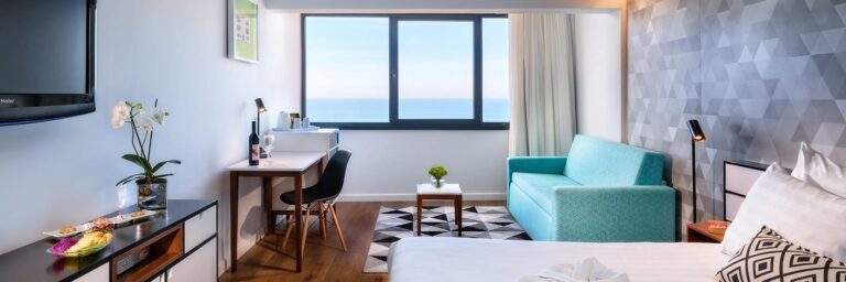 החדר במלון פרימה תל אביב עם מיטת קווין פינת ישיבה, פינת עבודה, טלוויזיה ונוף לים