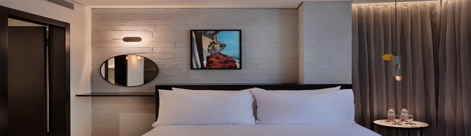 מבטח על החדר במלון בוטיק מיוז תל אביב הכולל מיטת קווין סייז, מראה עגולה, פינת ישיבה יצירה על הקיר ווילון